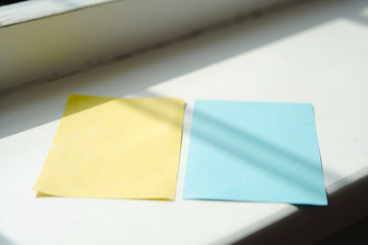 Two pieces of plain coloured card lying in direct sunlight on a painted windowsill.