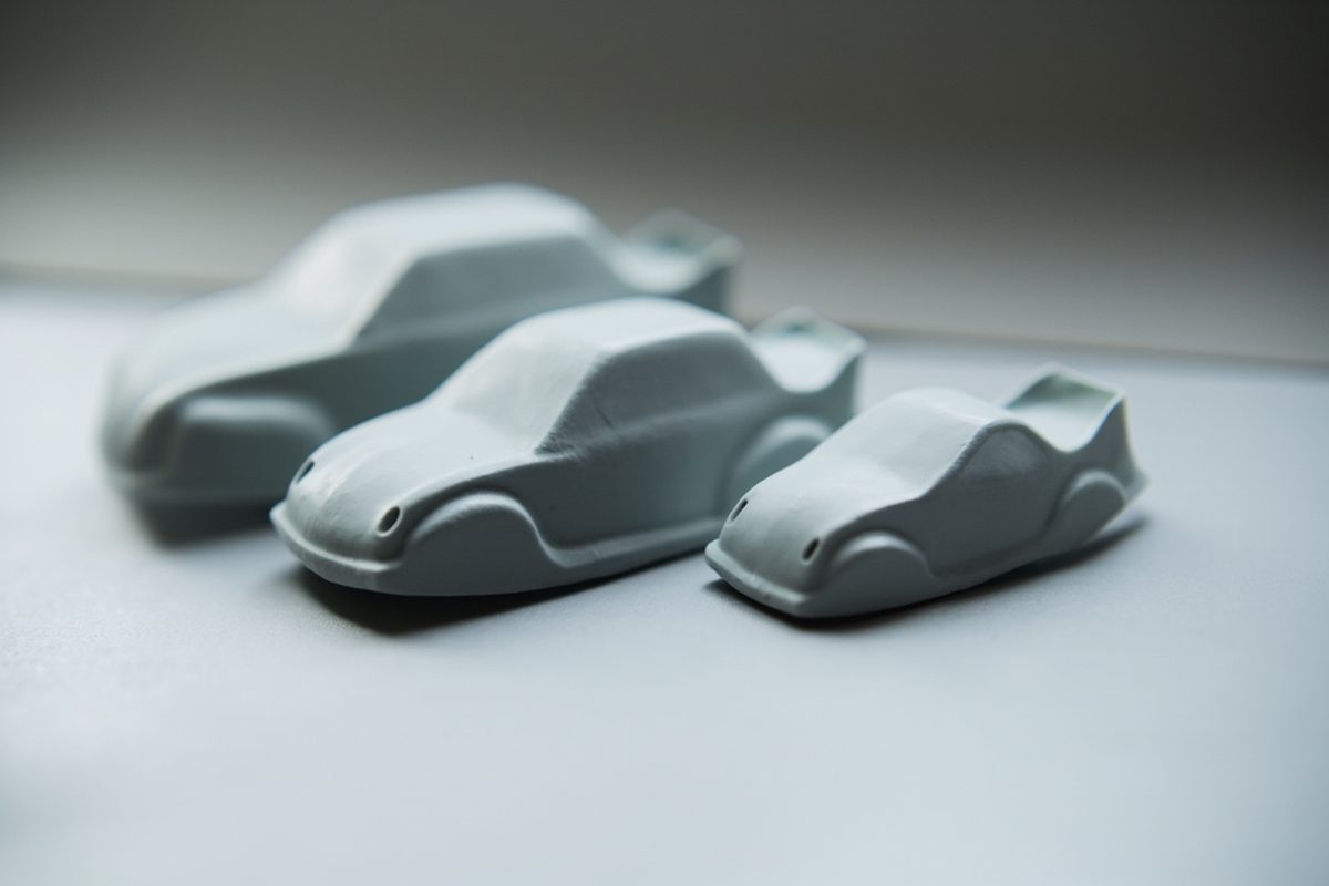 Three blank unpainted model car bodies arranged in a row from largest to smallest on a plain surface.