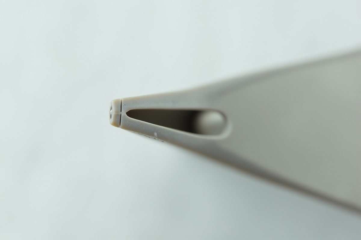 Extreme close-up of a plastic screw post and seam showing faint tool scoring around the edge.