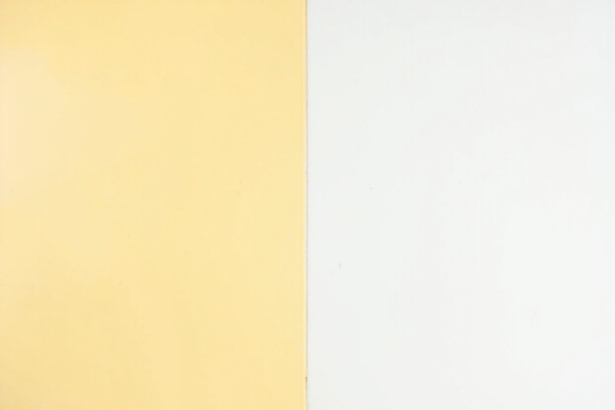 Two blank white plastic tiles side by side, one distinctly yellowed and one still bright white.