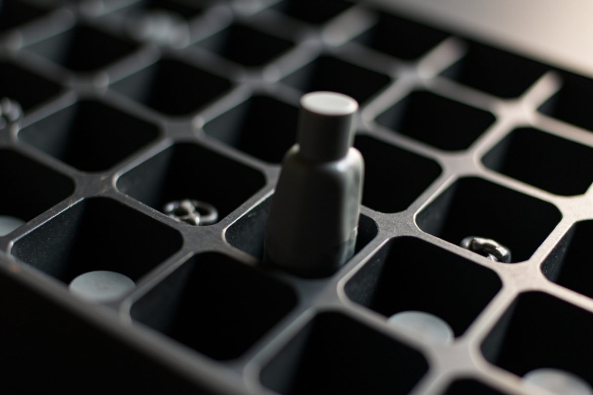 A single small grey plastic part standing in one cell of an otherwise empty compartment tray.