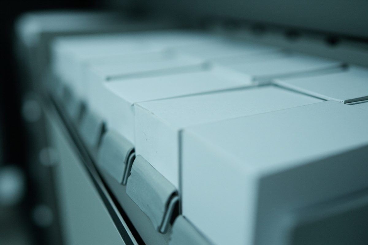 Plain white archival storage boxes standing upright in a row under cool, even light.