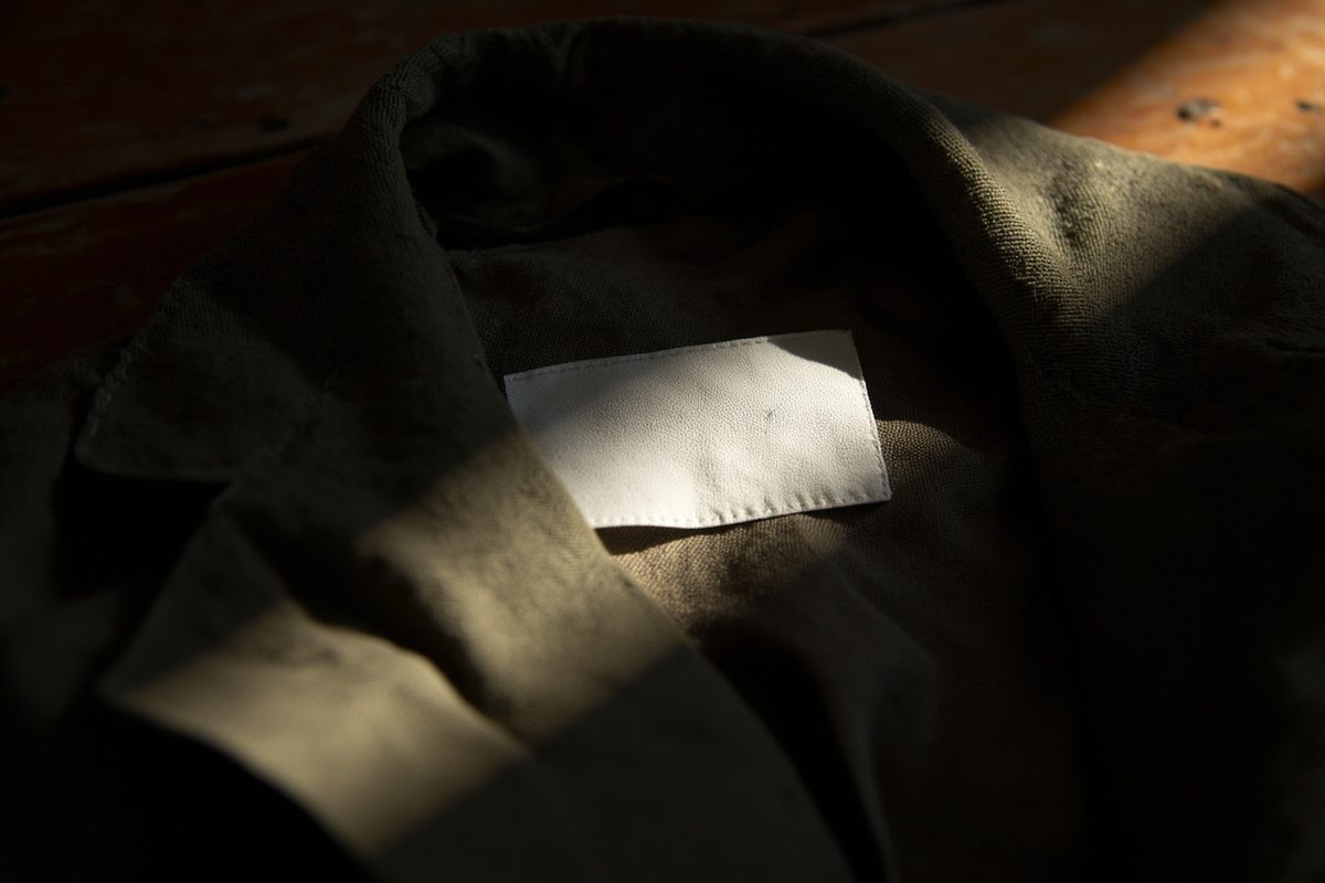Close-up of a blank woven garment tag sewn inside a heavy cotton duck jacket.
