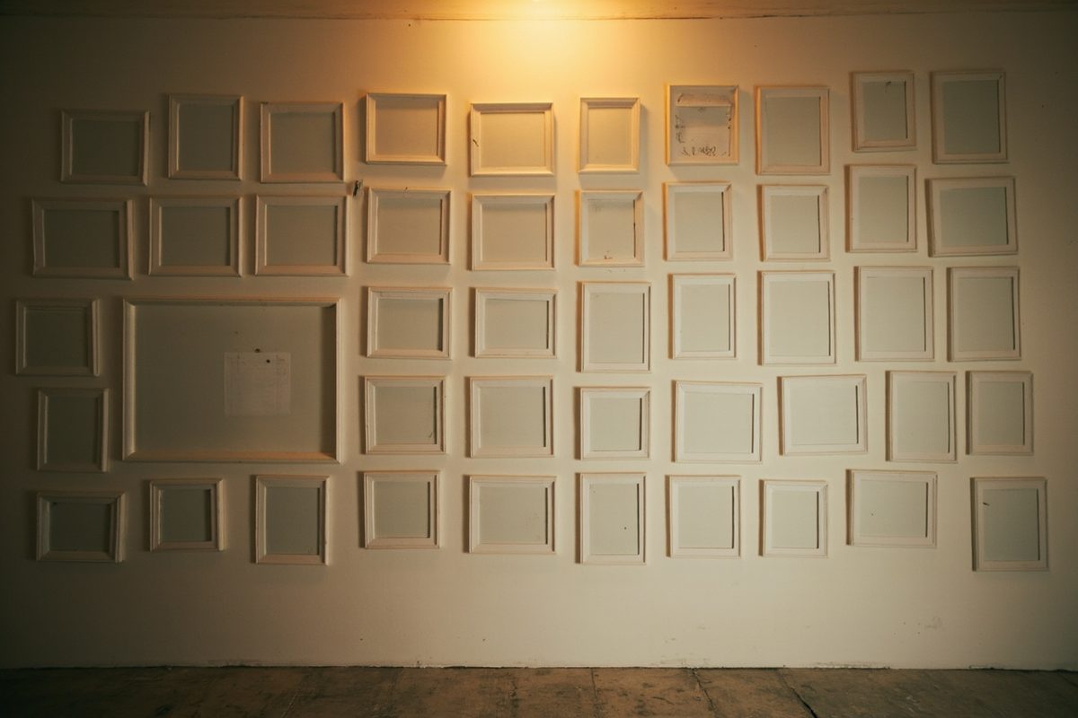 A wall filled with rows of empty picture frames, every one of them blank.