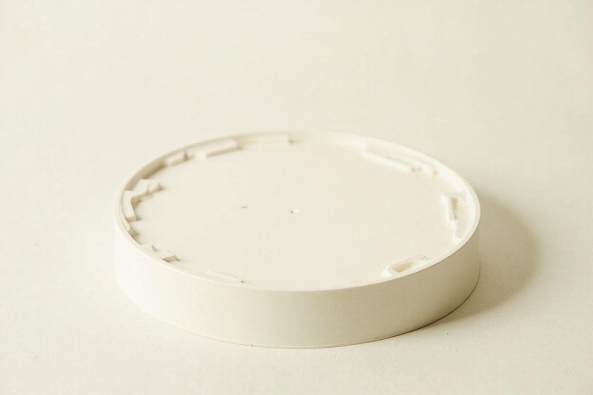 A plain unmarked circular moulded plastic display base resting on a neutral surface.