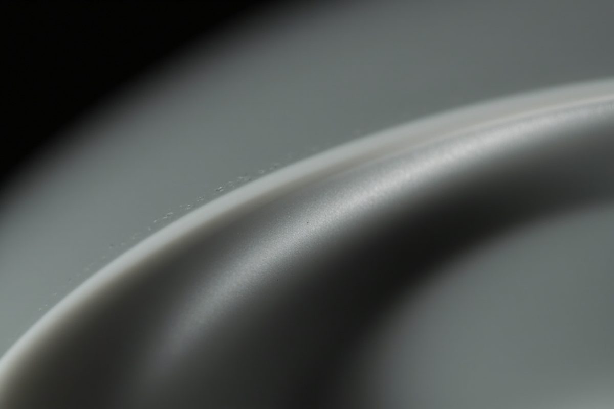 Extreme close-up of a moulded parting seam line running down a curved piece of matte grey painted plastic.