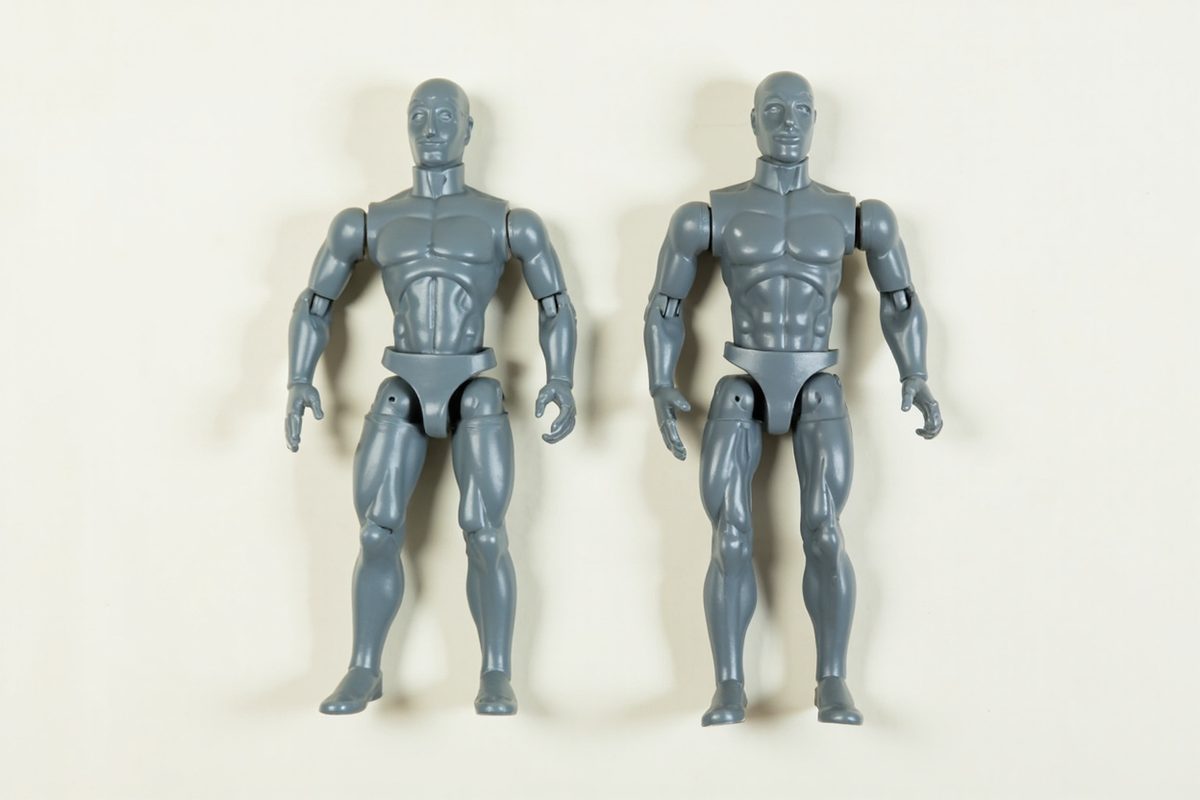 Two unpainted grey action figure blanks laid side by side, their moulded cut joints visible at the shoulders, elbows, hips and knees.